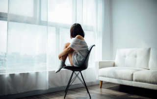 Keep-or-Sell-the-House, image of a woman in her own sitting on a chair staring out the window