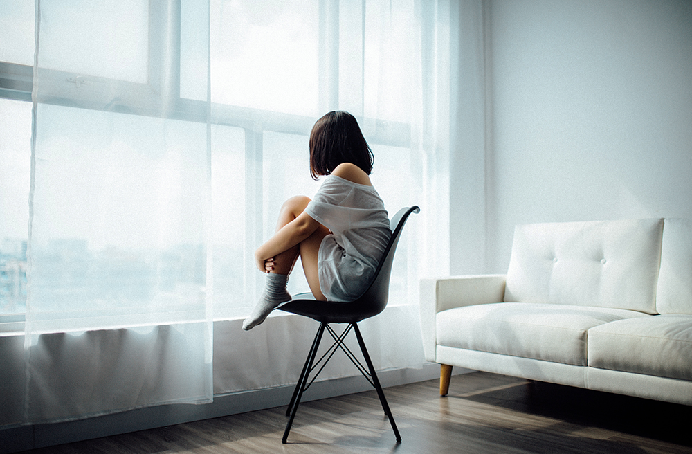 Keep-or-Sell-the-House, image of a woman in her own sitting on a chair staring out the window